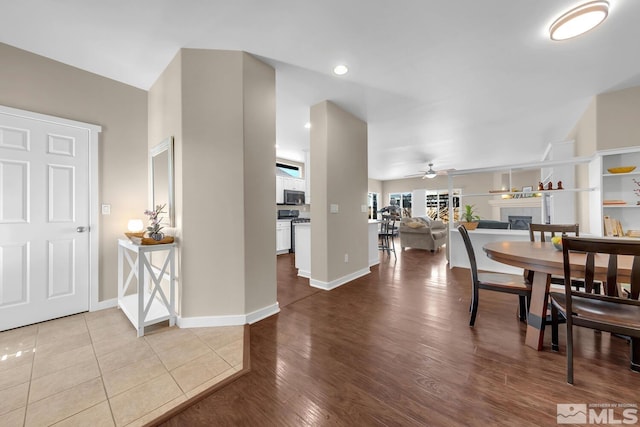 dining space featuring a tile fireplace, hardwood / wood-style floors, and ceiling fan