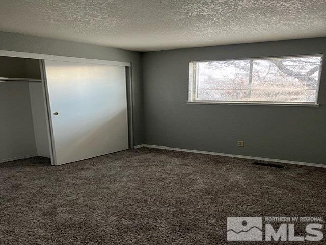 unfurnished bedroom with carpet floors, a closet, and a textured ceiling