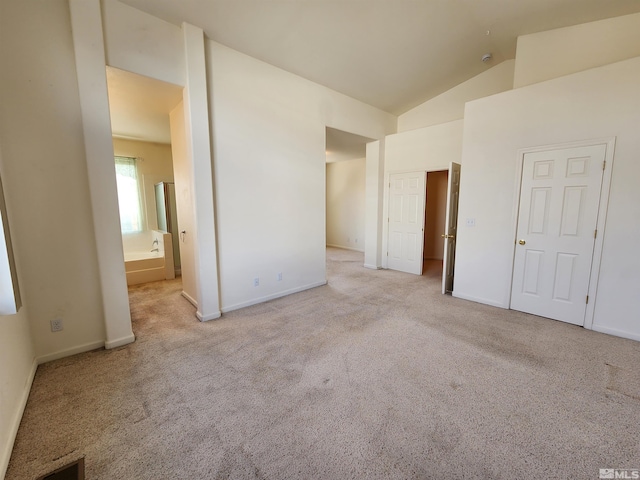 unfurnished bedroom featuring connected bathroom, high vaulted ceiling, and light carpet