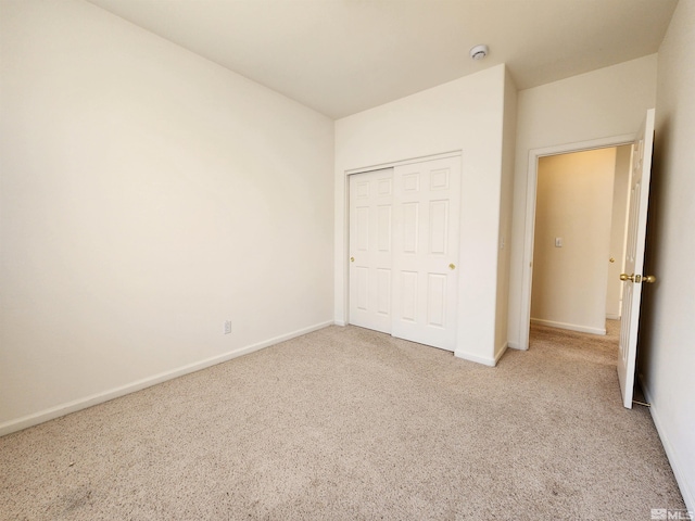 unfurnished bedroom featuring light colored carpet and a closet