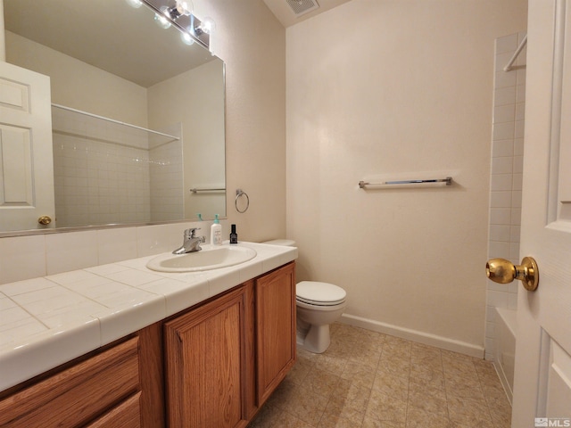 full bathroom with tiled shower / bath, vanity, and toilet