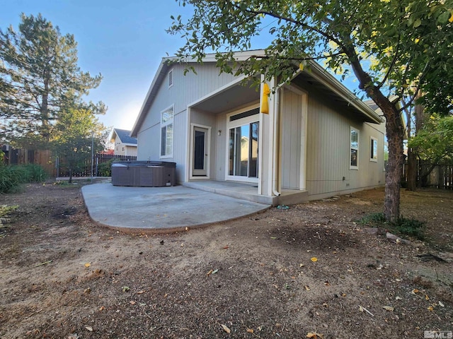 rear view of property with a hot tub and a patio