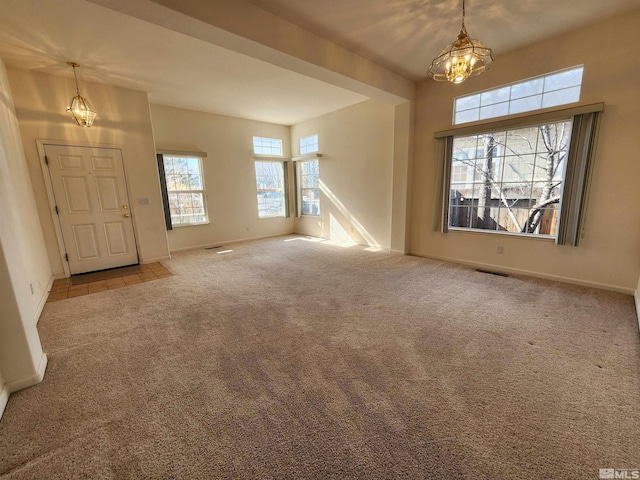 carpeted entrance foyer featuring a notable chandelier