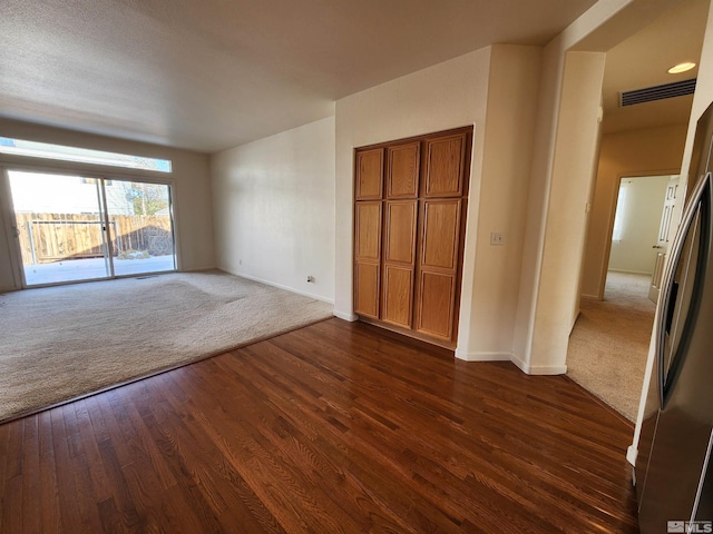 unfurnished bedroom with access to exterior, dark wood-type flooring, and stainless steel fridge