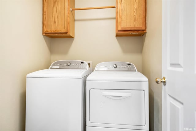 laundry area with independent washer and dryer and cabinets