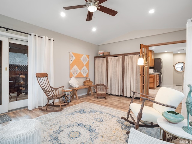 living area with light hardwood / wood-style flooring, vaulted ceiling, and ceiling fan