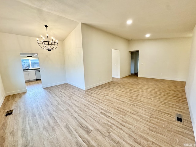 unfurnished room with vaulted ceiling, light wood-type flooring, sink, and an inviting chandelier