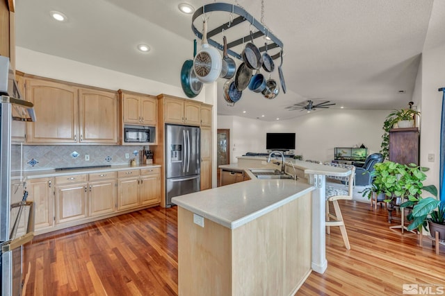 kitchen featuring sink, light brown cabinets, black microwave, and stainless steel refrigerator with ice dispenser