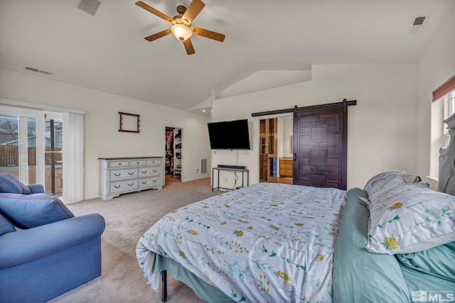 bedroom featuring lofted ceiling, light colored carpet, a walk in closet, a barn door, and ceiling fan