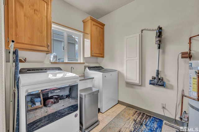 laundry area with washing machine and dryer, light tile patterned floors, water heater, and cabinets