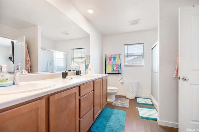 bathroom featuring toilet, wood-type flooring, an enclosed shower, and vanity