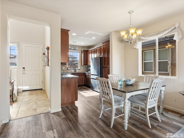 dining area with sink, an inviting chandelier, and wood-type flooring