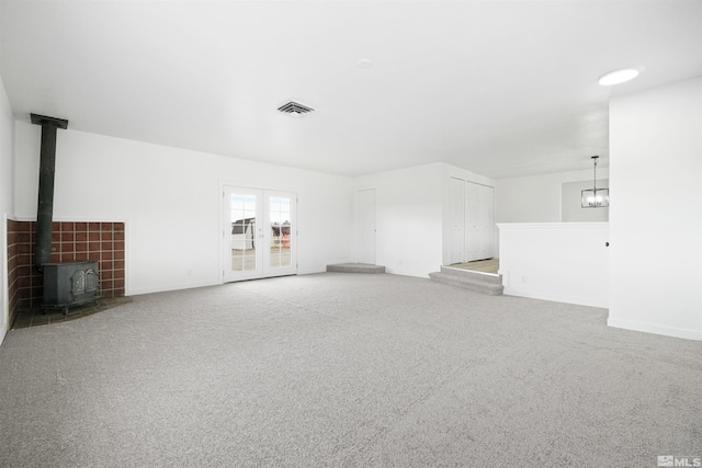 unfurnished living room with a wood stove and light colored carpet