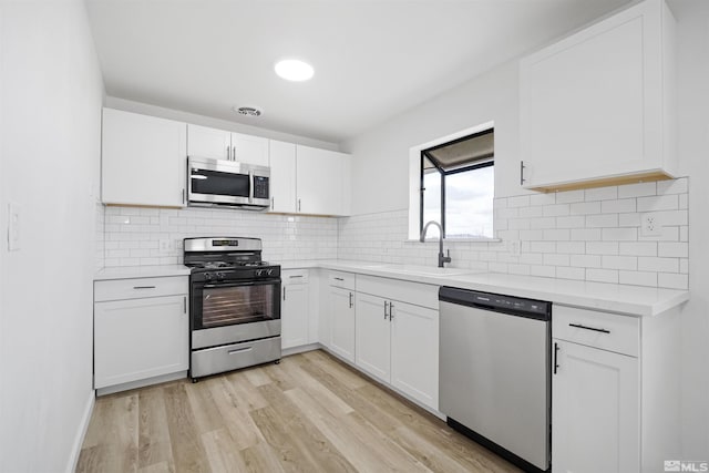 kitchen featuring white cabinetry, appliances with stainless steel finishes, sink, and light wood-type flooring