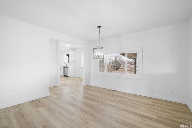 unfurnished dining area with light wood-type flooring and a notable chandelier