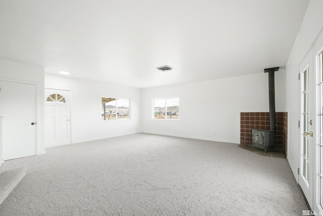 unfurnished living room with carpet flooring and a wood stove