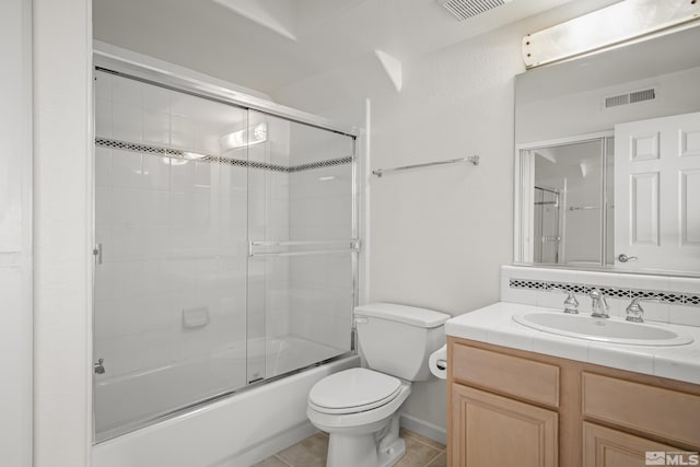 full bathroom with toilet, bath / shower combo with glass door, tile patterned flooring, and vanity