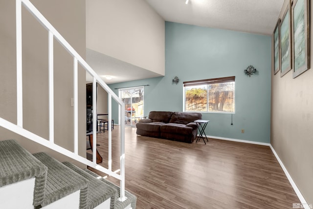 interior space featuring hardwood / wood-style floors, high vaulted ceiling, and a textured ceiling