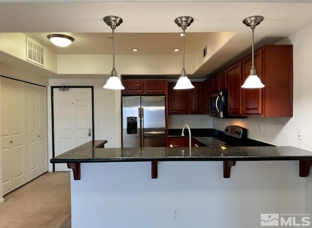 kitchen with a kitchen bar, sink, pendant lighting, stainless steel appliances, and kitchen peninsula