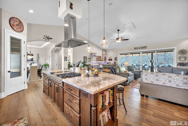 kitchen featuring light wood-type flooring, island range hood, a center island, hanging light fixtures, and stainless steel gas stovetop