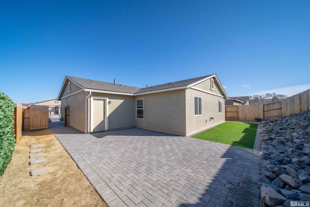 rear view of property featuring a yard, a patio area, a fenced backyard, and stucco siding