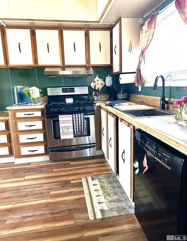 kitchen with black dishwasher, light hardwood / wood-style floors, sink, stainless steel gas range, and white cabinets