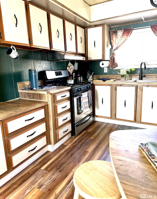 kitchen with dark hardwood / wood-style flooring, white cabinets, sink, and stainless steel gas range