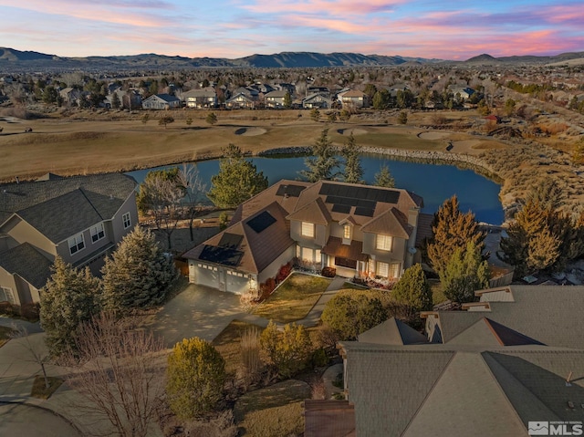 aerial view at dusk featuring a water and mountain view