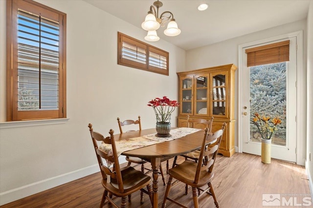 dining area with a notable chandelier, light wood finished floors, a wealth of natural light, and baseboards