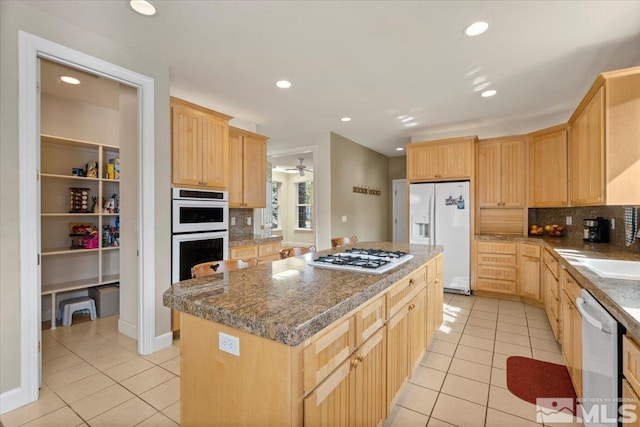 kitchen featuring light brown cabinets, white appliances, light tile patterned floors, and a kitchen island