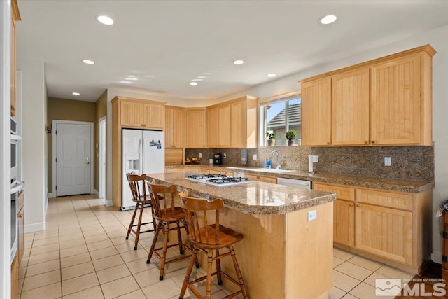 kitchen with a center island, a breakfast bar area, appliances with stainless steel finishes, light tile patterned flooring, and dark stone counters