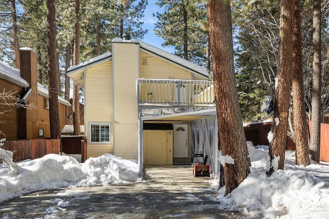 snow covered property featuring a balcony and fence