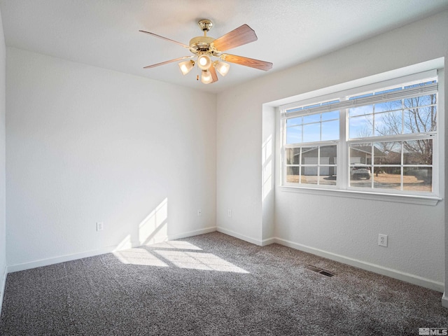 carpeted spare room featuring baseboards, visible vents, and ceiling fan