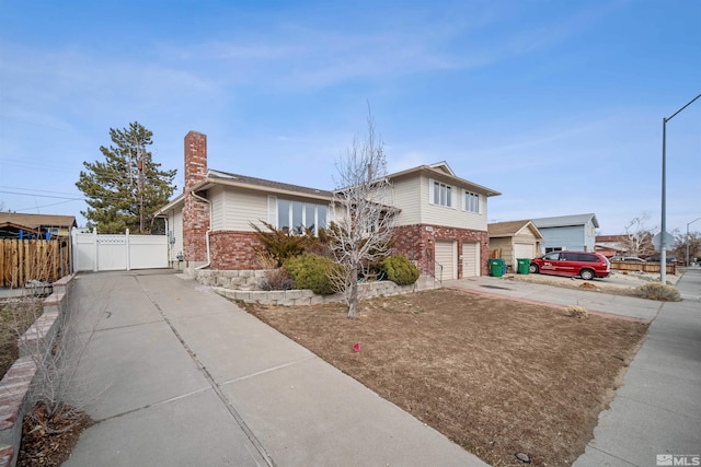 view of front facade featuring brick siding, a chimney, an attached garage, fence, and driveway