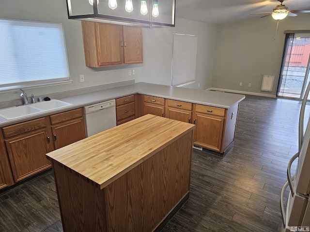 kitchen with dark wood finished floors, dishwasher, a kitchen island, brown cabinets, and a sink