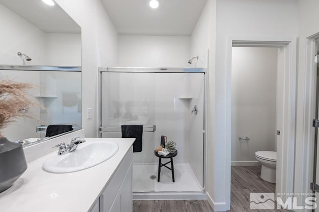 bathroom featuring vanity, a stall shower, wood finished floors, and toilet