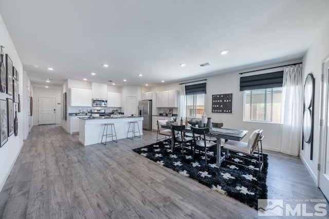 dining room with light wood finished floors, baseboards, visible vents, and recessed lighting