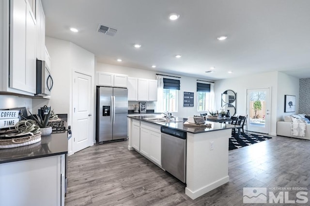 kitchen featuring an island with sink, appliances with stainless steel finishes, and white cabinets