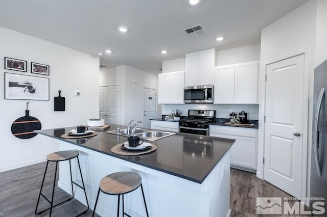 kitchen with stainless steel appliances, a sink, and a center island with sink