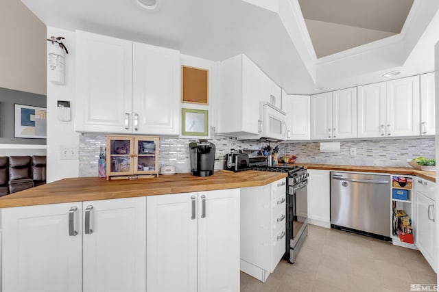 kitchen featuring stainless steel appliances, white cabinetry, wooden counters, and backsplash