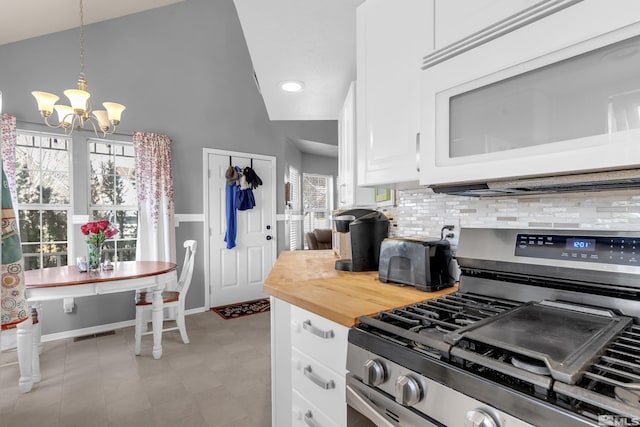 kitchen featuring stainless steel gas stove, decorative backsplash, white microwave, hanging light fixtures, and white cabinetry