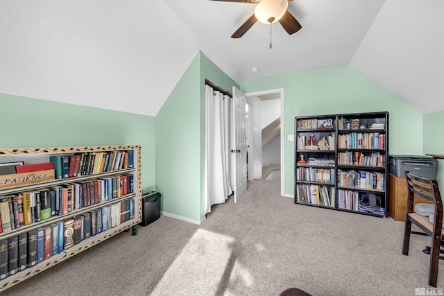 living area featuring lofted ceiling, ceiling fan, baseboards, and light colored carpet