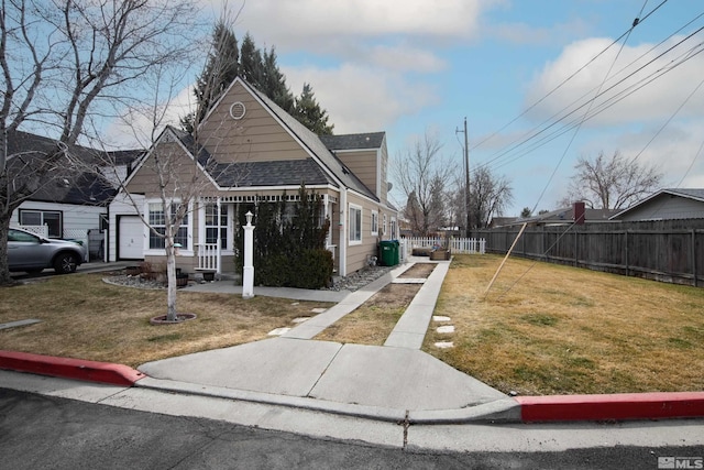 view of front facade featuring a shingled roof, fence, and a front lawn