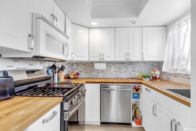 kitchen featuring stainless steel appliances, butcher block counters, white cabinets, and backsplash