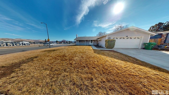 ranch-style home with a garage, concrete driveway, and a front yard