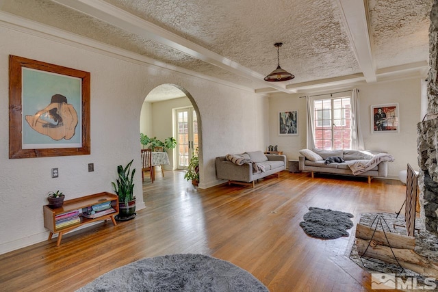 living room with a textured ceiling, arched walkways, wood finished floors, and a textured wall