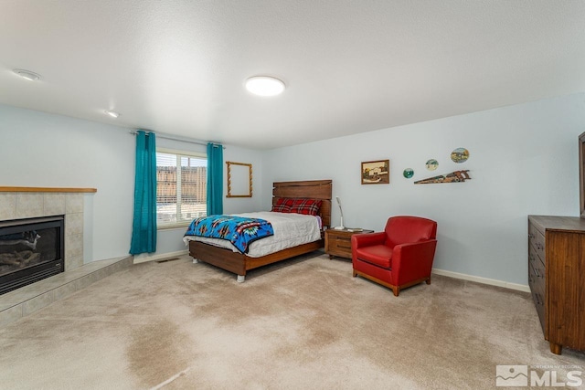 bedroom with light colored carpet, a fireplace, visible vents, and baseboards