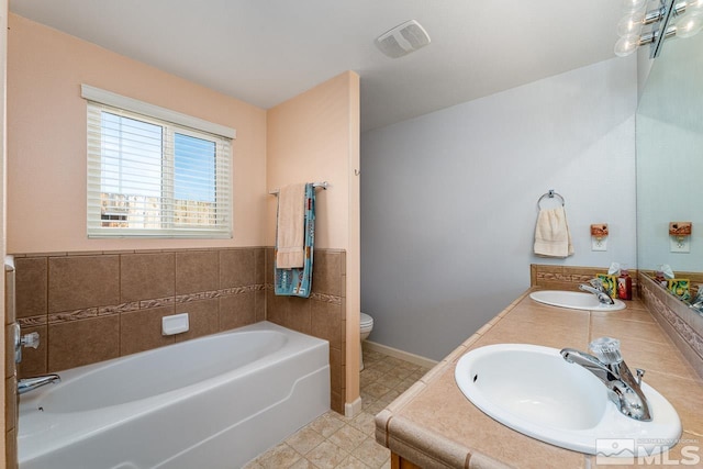 bathroom featuring a bath, a sink, toilet, and baseboards