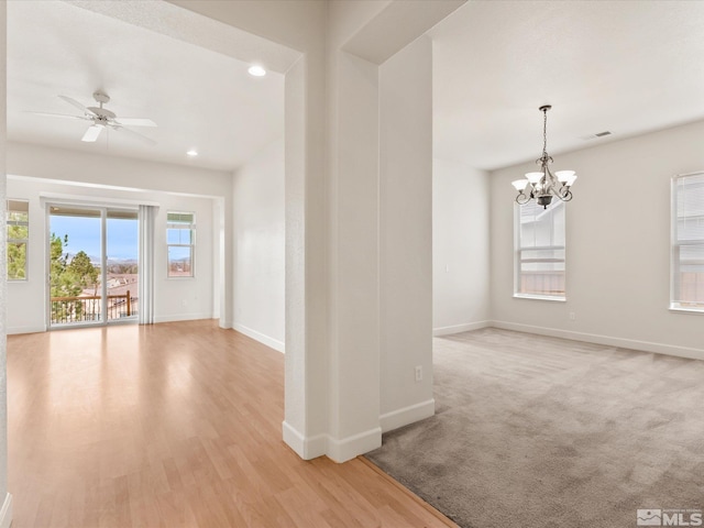 unfurnished room with baseboards, visible vents, light wood-style flooring, ceiling fan with notable chandelier, and recessed lighting