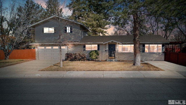 traditional-style house featuring driveway, an attached garage, and fence